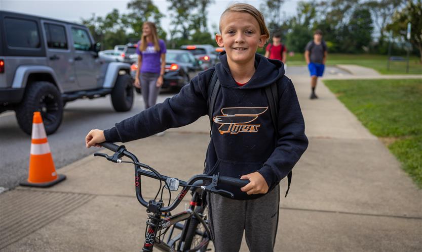 A boy stands next to his bike